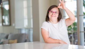 Une fille handicapée est assise à une table chez elle.