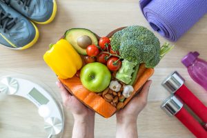 Une personne tient un bol de fruits et légumes en forme de cœur.